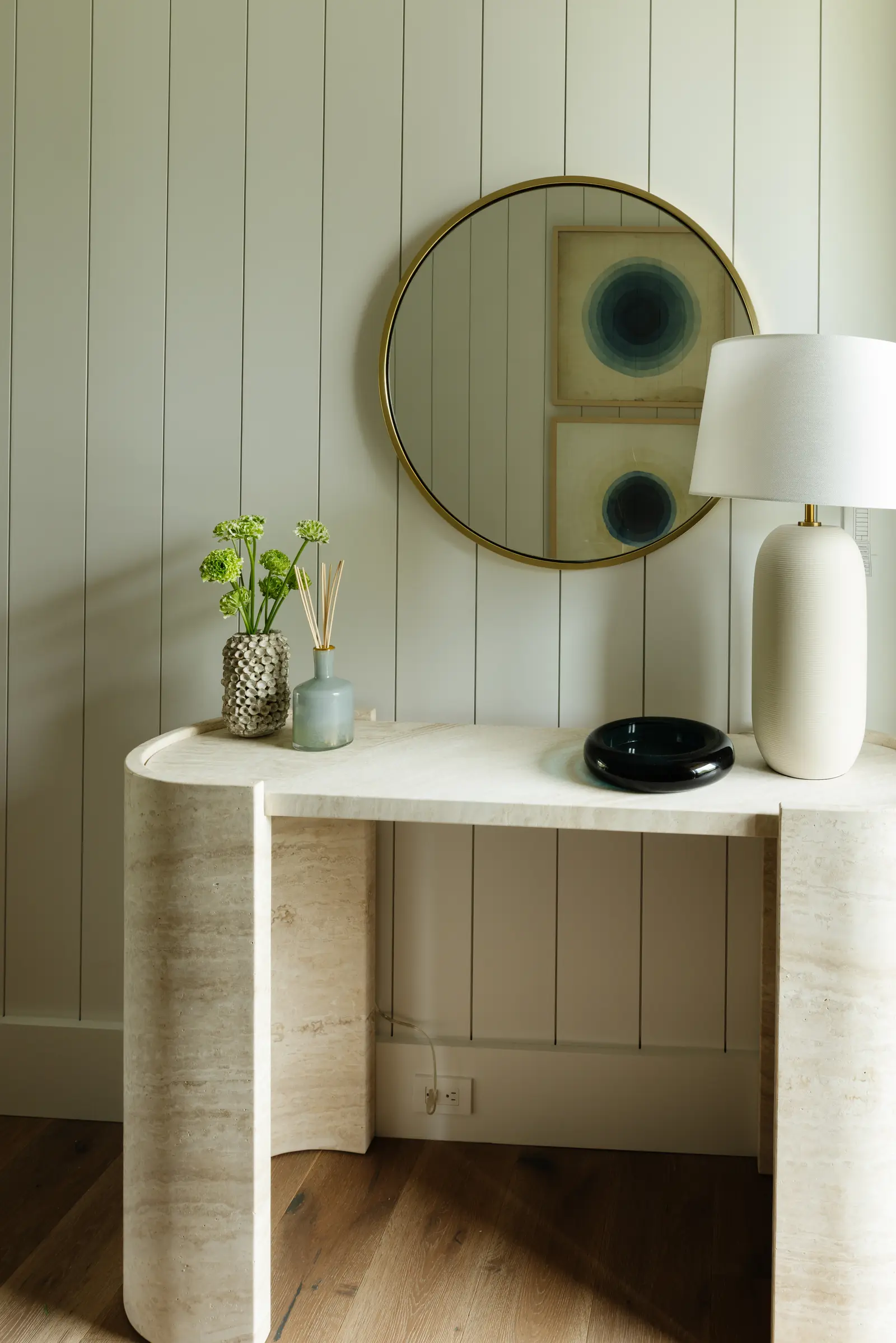 Travertine console with a round mirror and a white lamp