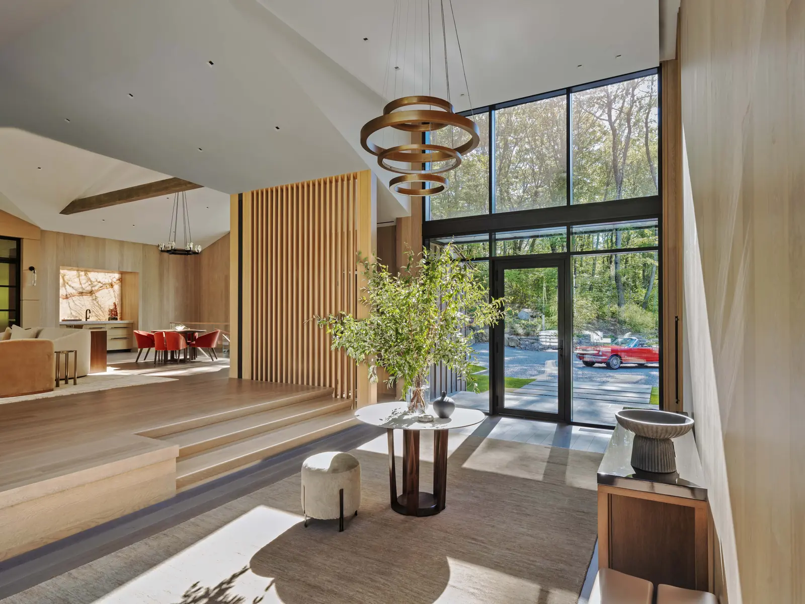 Double-height entry with white oak slats and a sculptural pendant