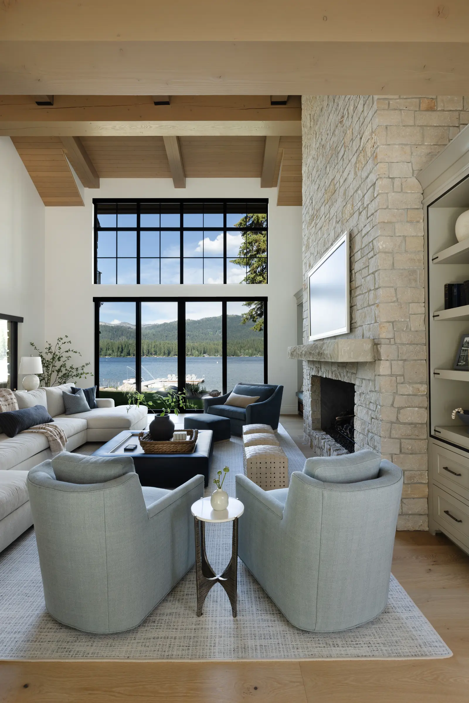 Great room with a stone fireplace and windows onto the lake