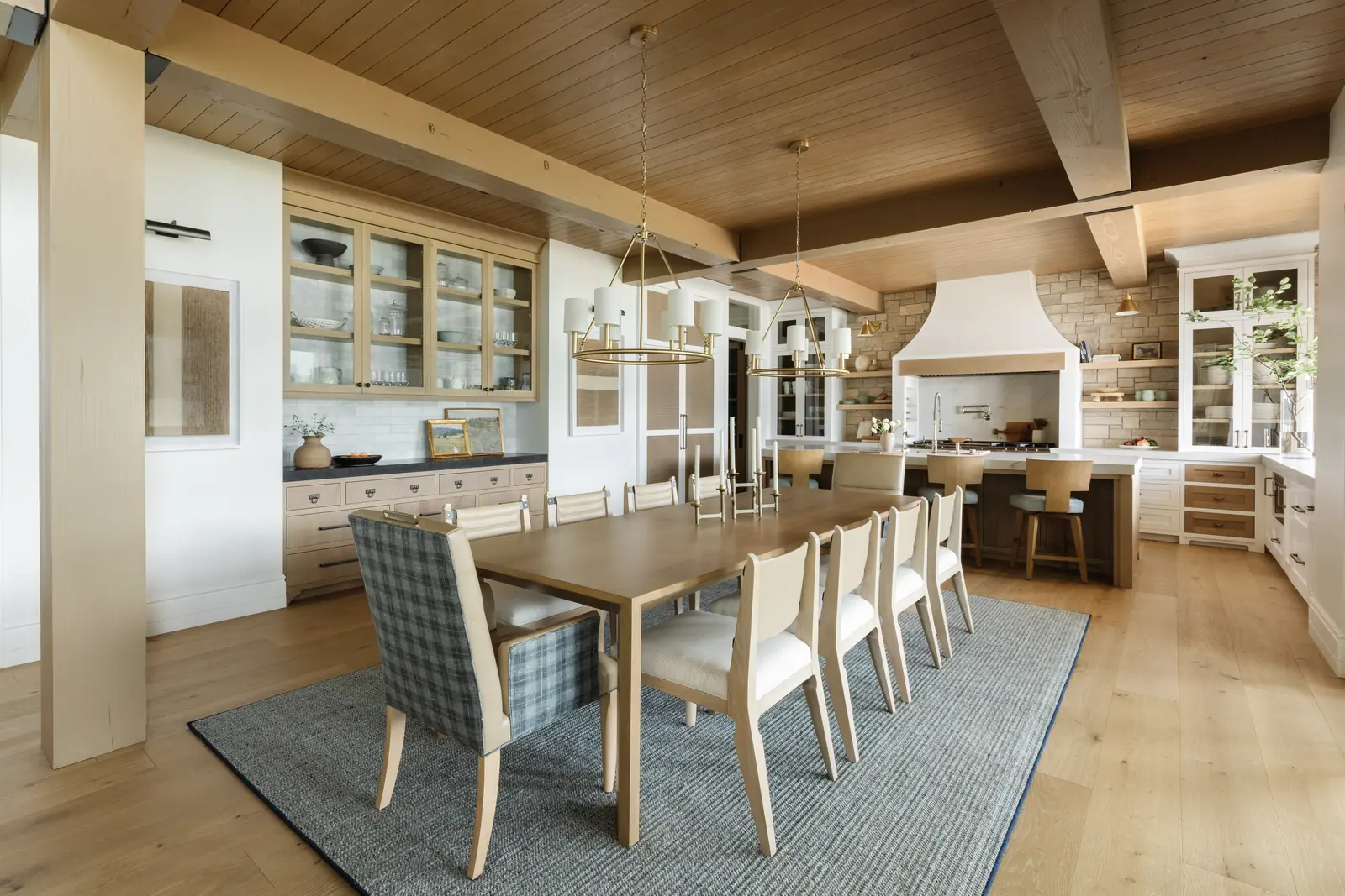 Long dining table under timber beams beside the kitchen